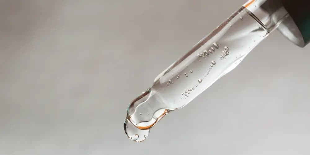 A pipette with serum on a grey background.